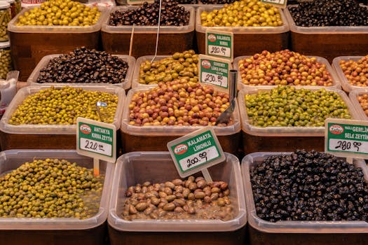 Variety of olives in containers with price tags at a market in İzmir, Türkiye.