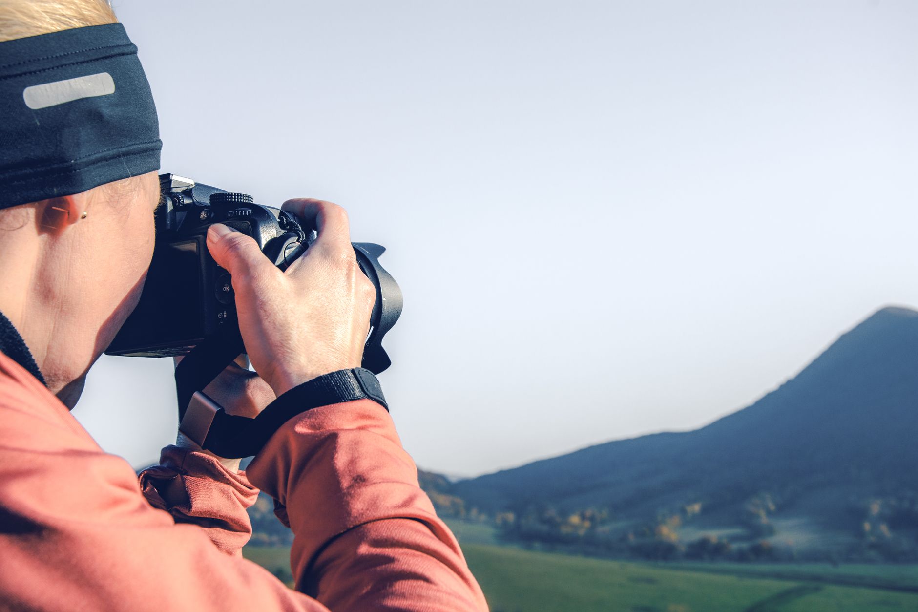 風景攝影進階:超廣角畸變控制與前景設計技巧 A woman photographer takes a photo of a scenic mountain landscape outdoors during the day.