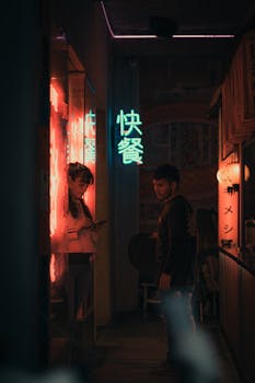 Young adults in a neon-lit alley exuding mystery and urban vibes.
