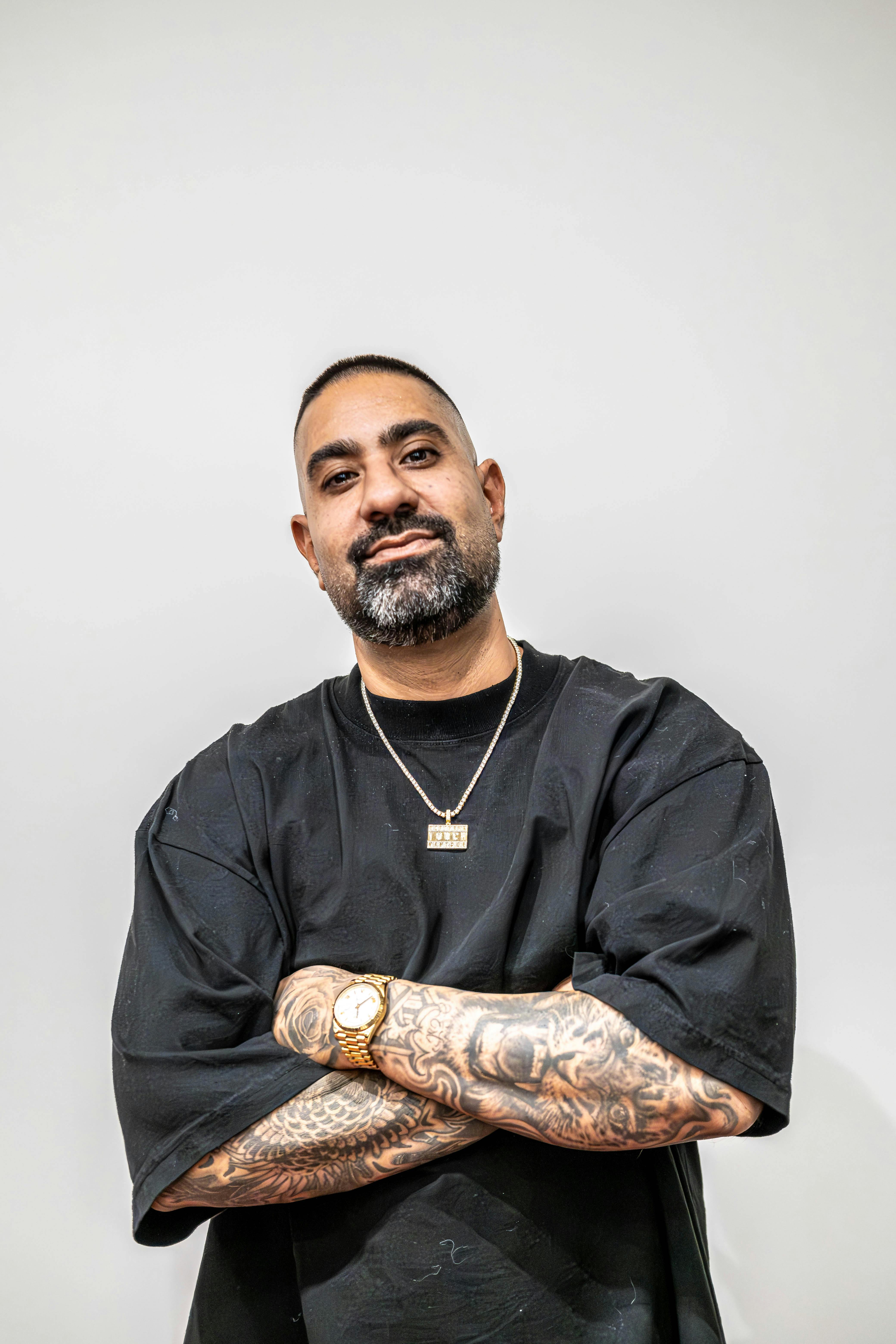 Artistic portrait of tattooed man with beard in studio, showcasing urban fashion.