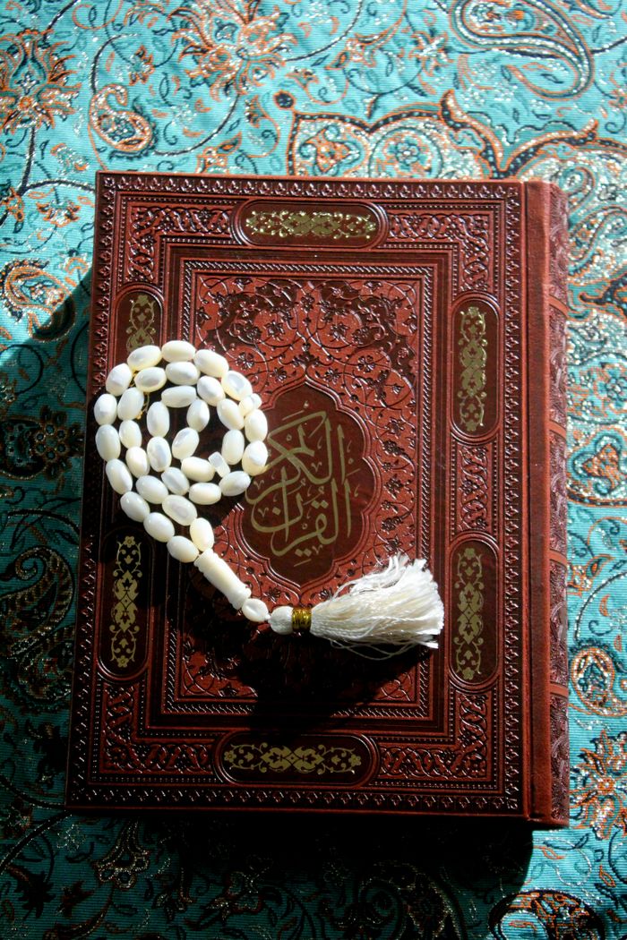 Quran with prayer beads on patterned fabric