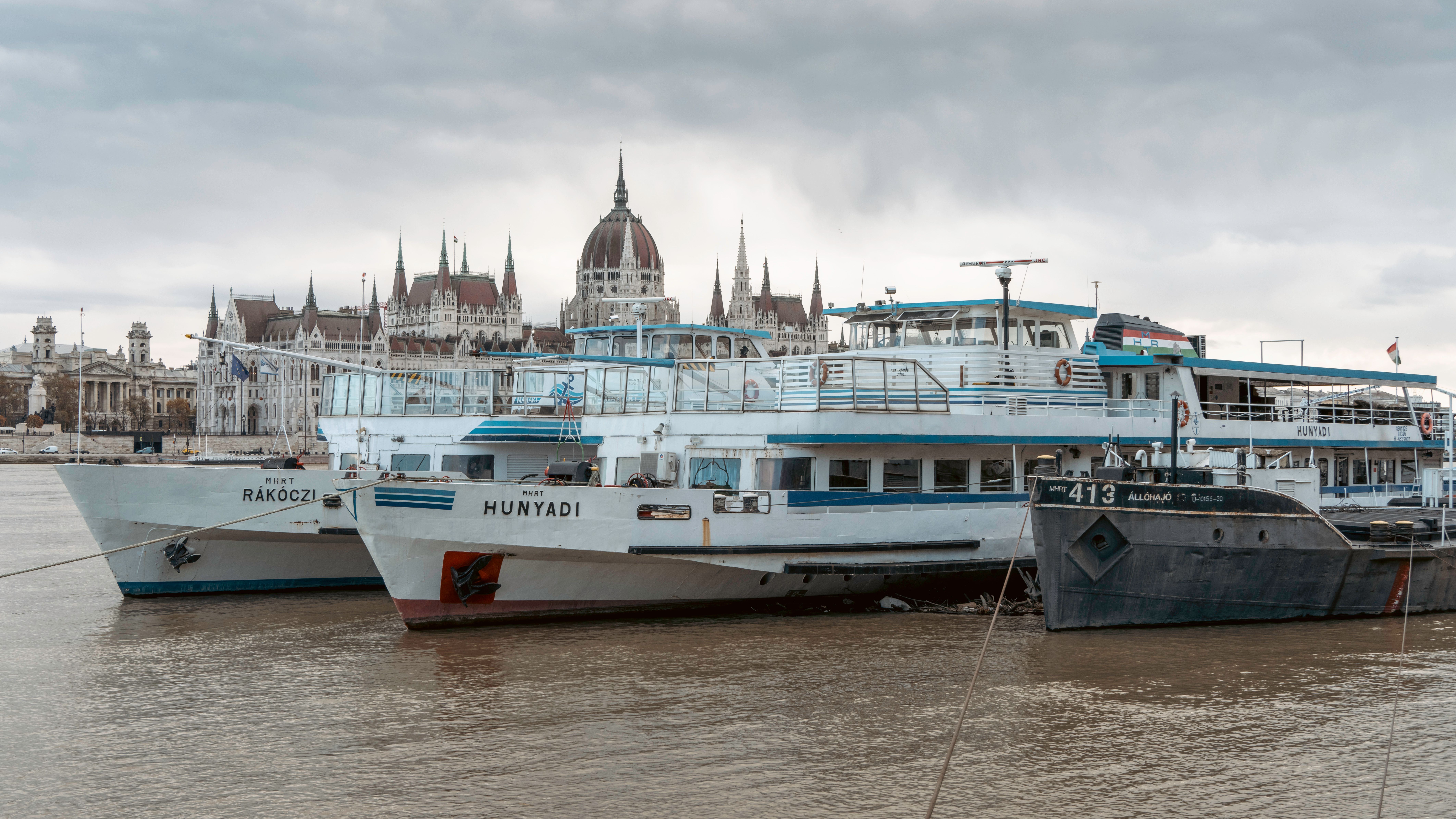 Anchored boats on the Danube River with Budapest's Parliament Building as a backdrop.