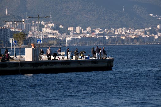 People fishing on a pier with Izmir cityscape as backdrop in Turkey.