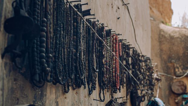 Vintage beaded jewelry hangs on an outdoor wall, showcasing intricate designs and craftsmanship.