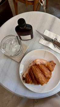Stylish flat lay of croissant with iced coffee on marble table.