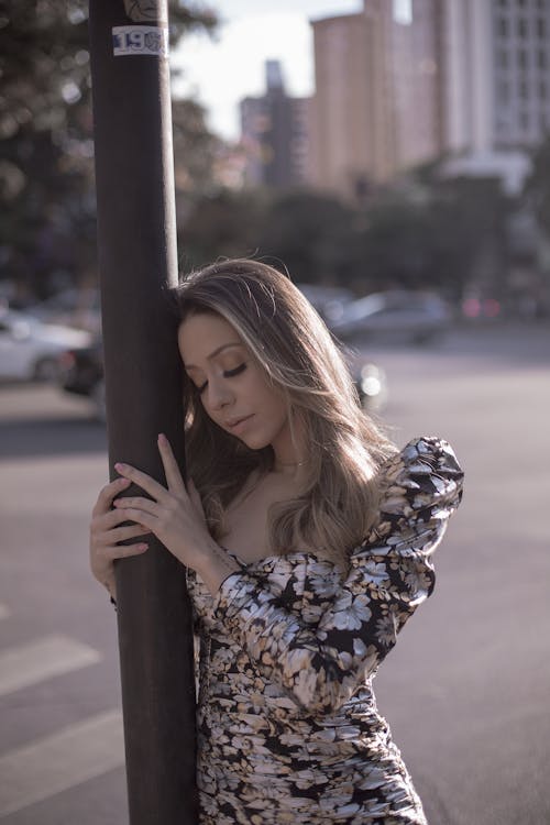 Selective Focus of Woman Leaning on Pole with Her Eyes Closed Posing