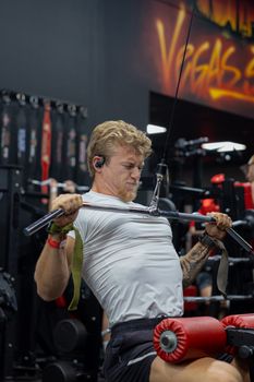 Focused man exercising on a lat pulldown machine at the gym.