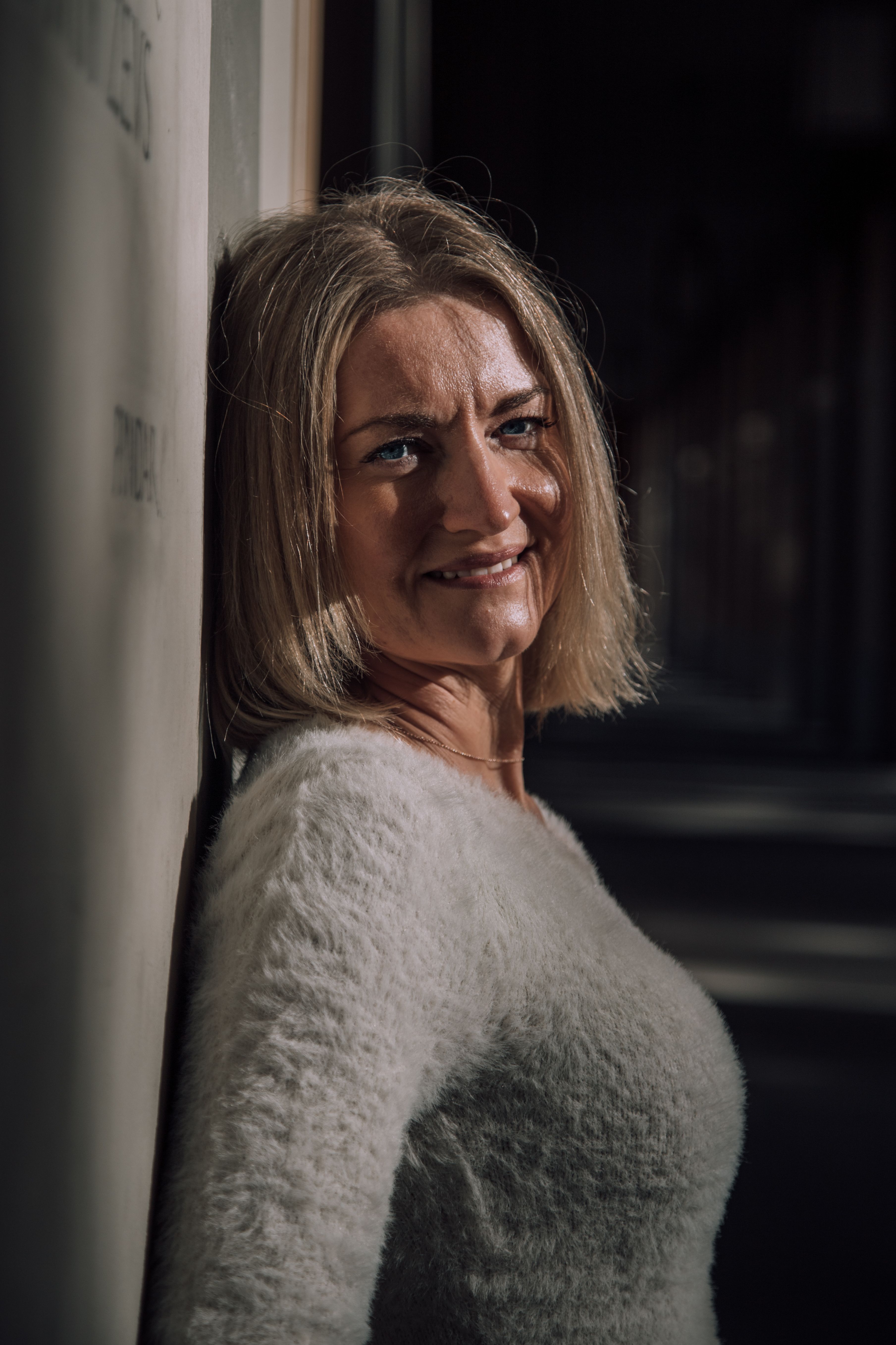 Close-up portrait of a woman leaning on a wall with sunlight in München, Germany.