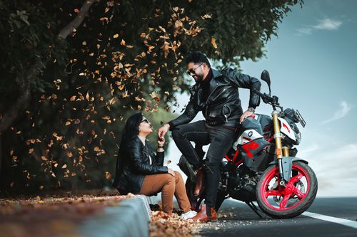 Free Couple enjoying a romantic moment with a motorcycle surrounded by autumn leaves. Stock Photo