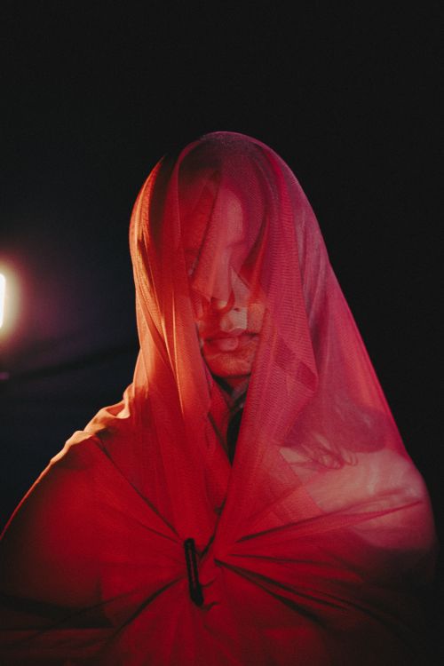 Free Captivating portrait of a person draped in red fabric, creating a mysterious atmosphere. Stock Photo