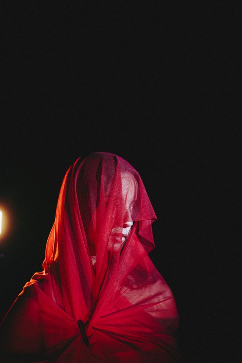 Free A mysterious figure draped in a red veil with dramatic lighting. Artistic and moody. Stock Photo