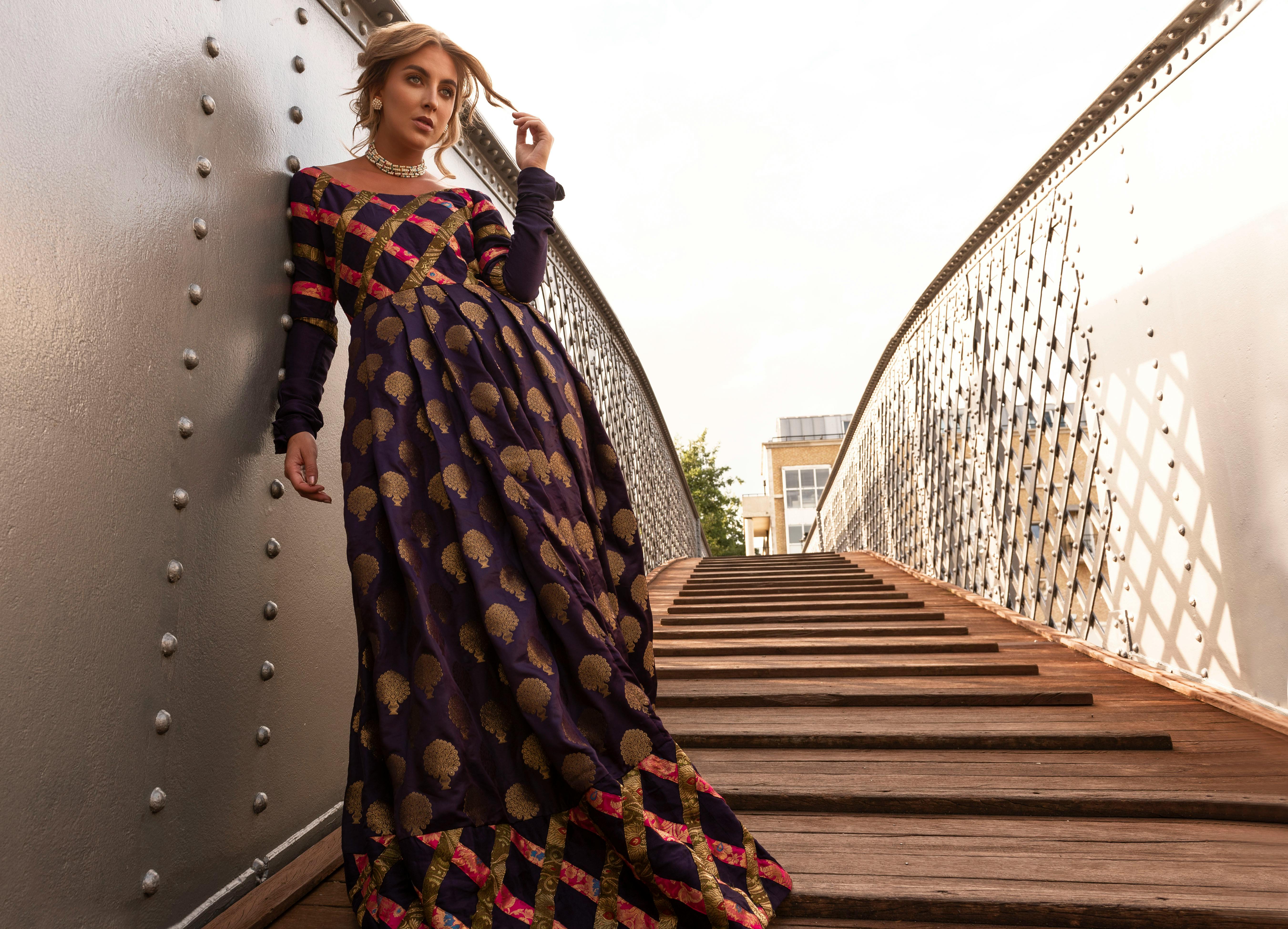 一位时尚女子身着漂亮礼服，在风景秀丽的桥上优雅地摆着姿势