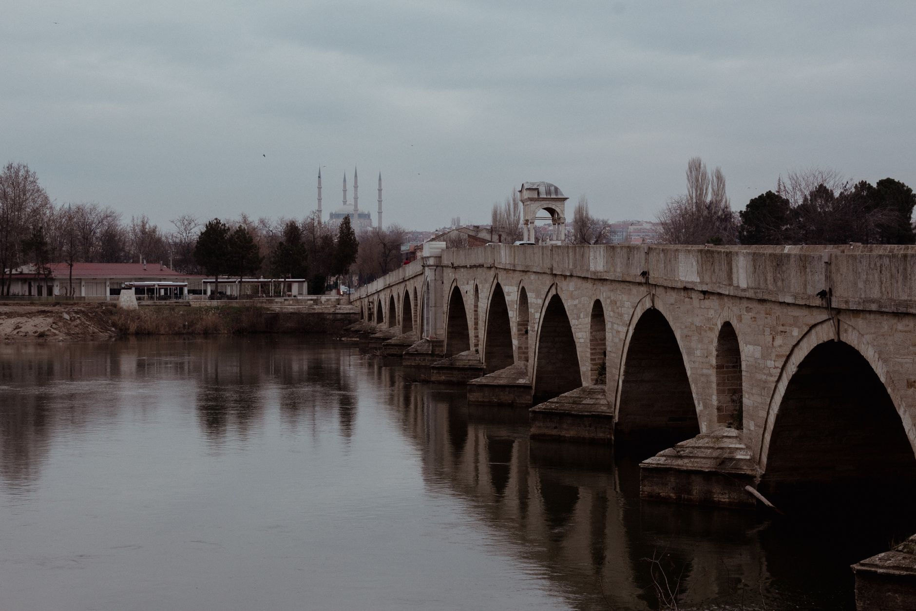 A historic stone arch bridge reflecting in a calm river in Edirne, Türkiye.