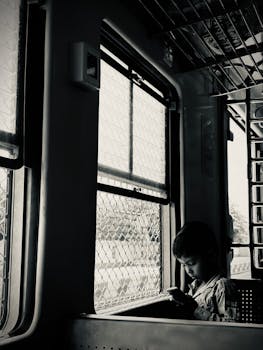 A young boy gazes out a train window during a peaceful journey in Chennai, India.