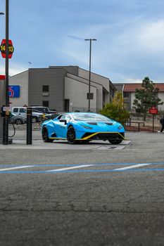 Vibrant blue sports car parked at a gas station on a clear day, showcasing urban backdrop.