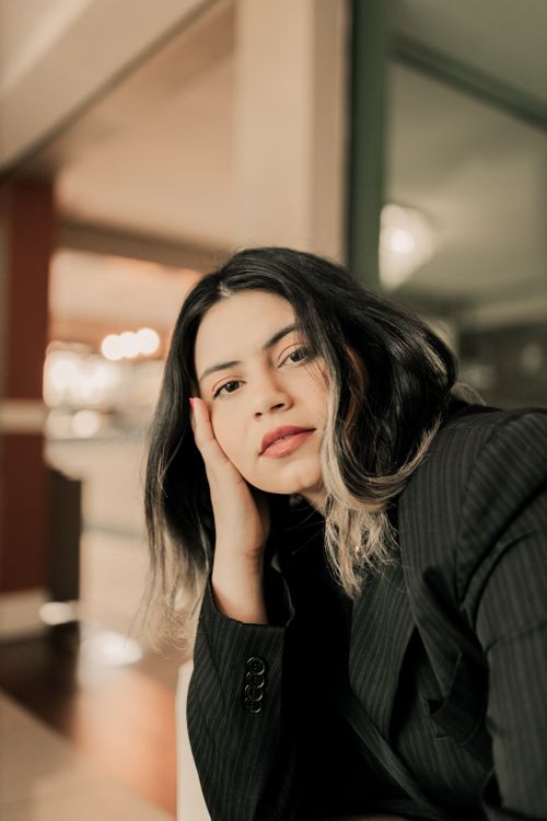 Free A contemplative woman in a modern interior, face resting on her hand. Stock Photo