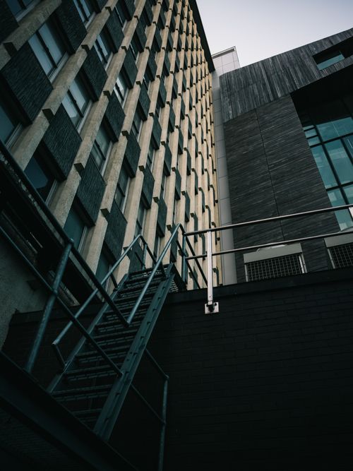 Free Low angle view of a modern building's exterior with fire escape stairs under a clear sky. Stock Photo