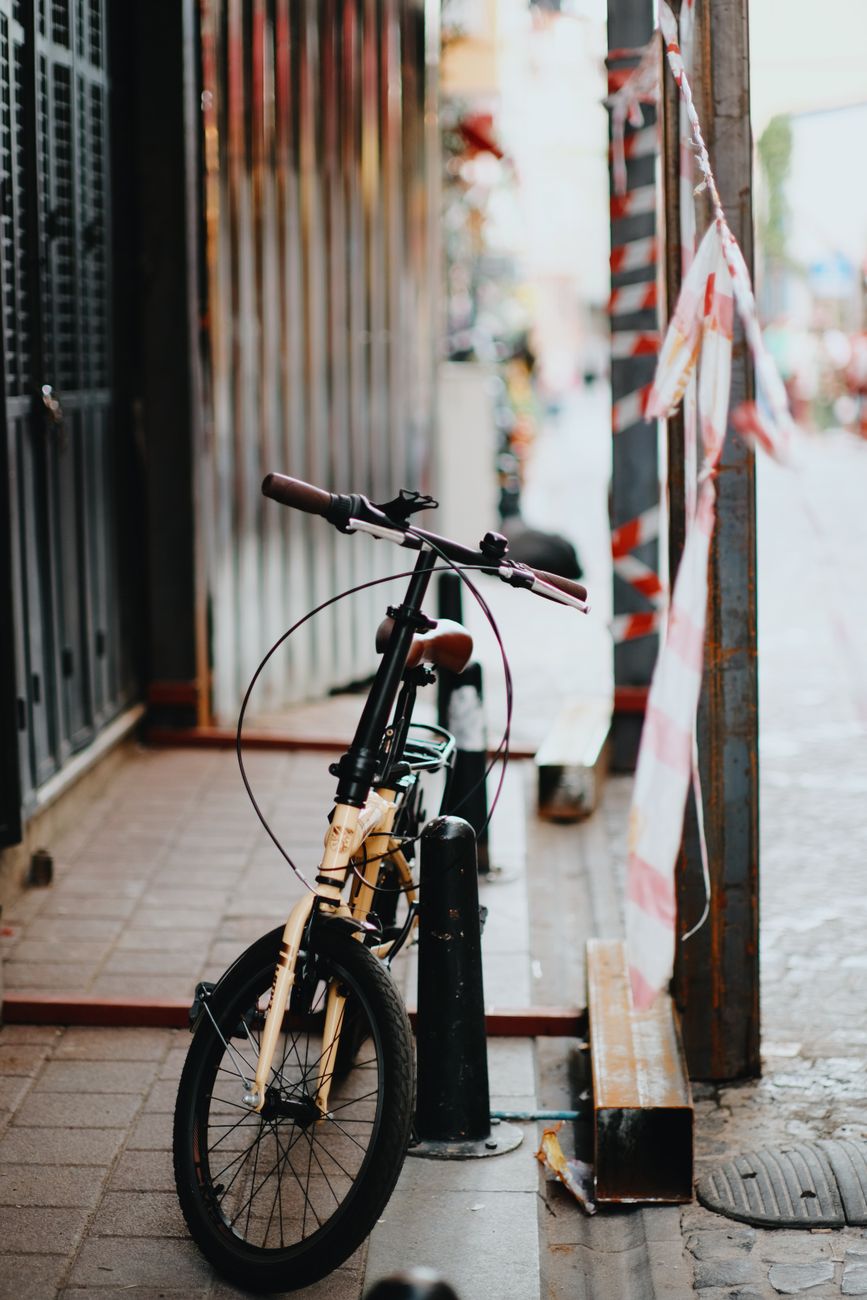 Vélo pliable garé sur un trottoir de la ville à côté de barrières métalliques. Thème du cyclisme urbain.