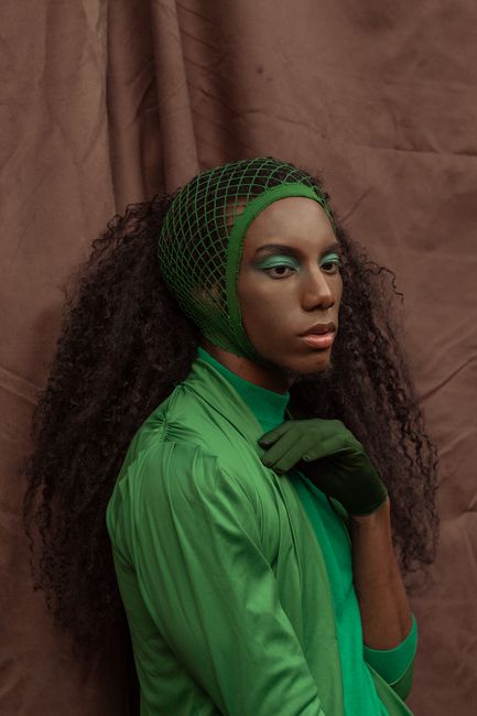 Striking editorial photo of a gender fluid model in green with unique styling.