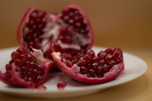 Free High-quality close-up of fresh pomegranate seeds on a white plate. Stock Photo