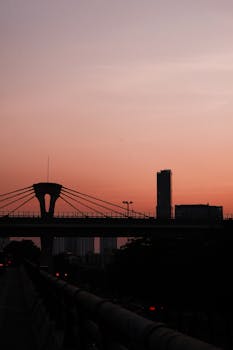 A striking silhouette of a bridge and buildings against a vibrant sunset.