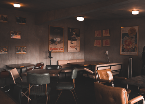Retro cafe interior with vintage decor and posters on concrete walls, warm lighting.