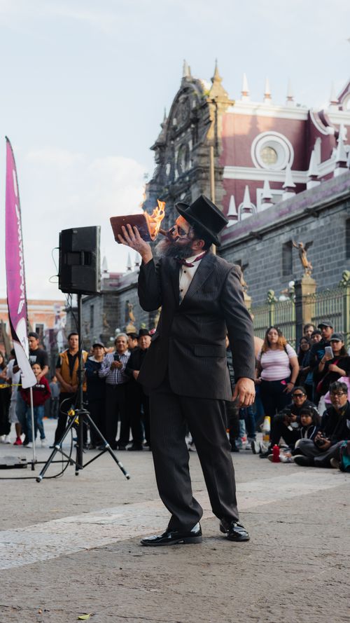 Free A street performer entertains a crowd with a flaming book in a historic city square. Stock Photo