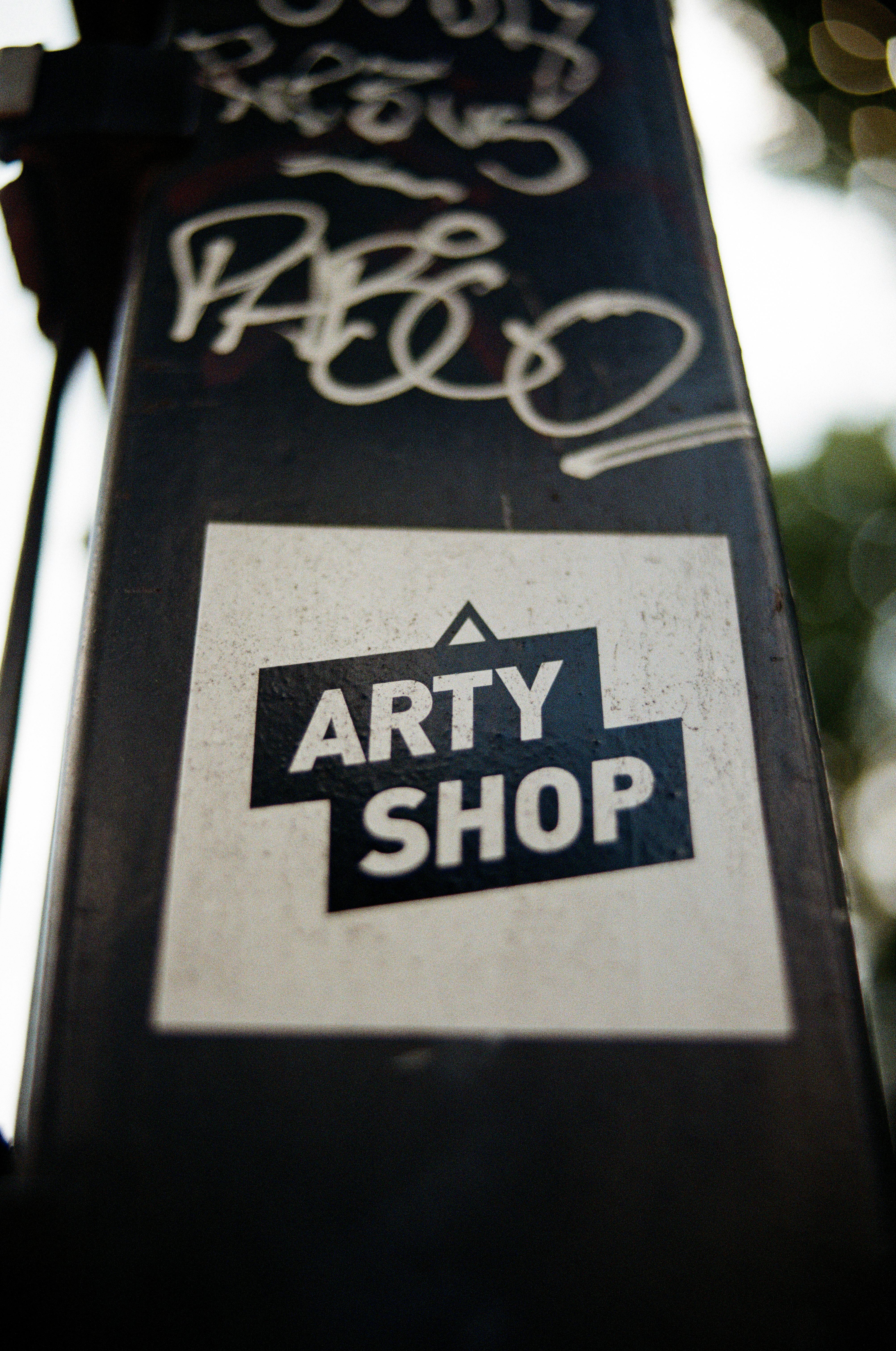 Close-up of an Arty Shop sticker on urban graffiti wall in Berlin, Germany.
