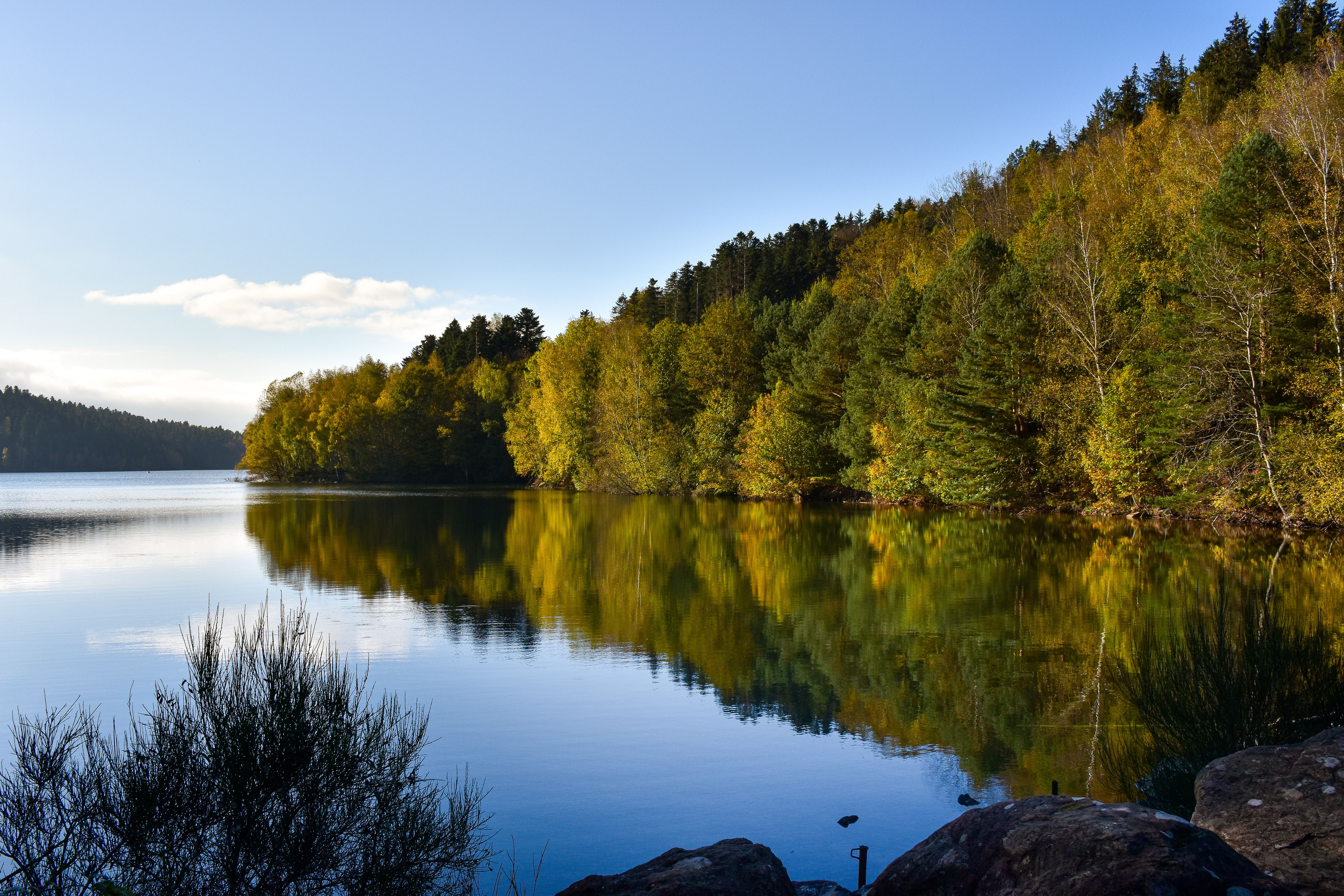 Fotomural Tranquilo paisaje otoñal del lago Pierre-Percée con vibrantes reflejos de follaje.