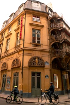 Parisian corner building with cyclists passing by, capturing a typical Paris street scene.