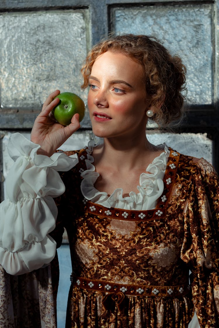 Dreamy Woman In Historical Costume With Apple Near Window