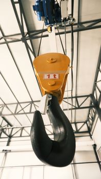 Close-up of a yellow overhead crane hook in a Konya warehouse, emphasizing strength and industrial use.
