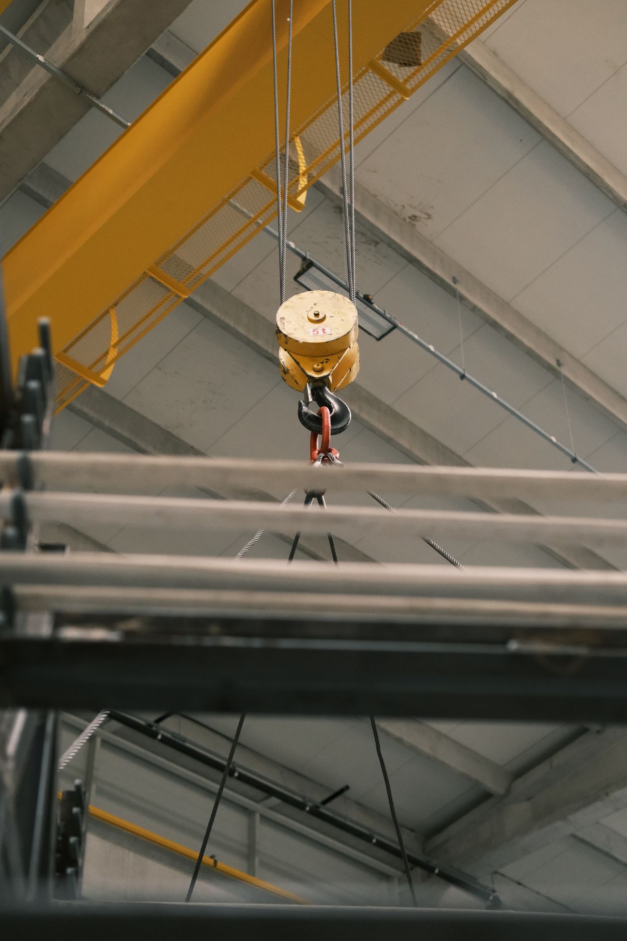 Crane hook lifting steel beams under controlled supervision