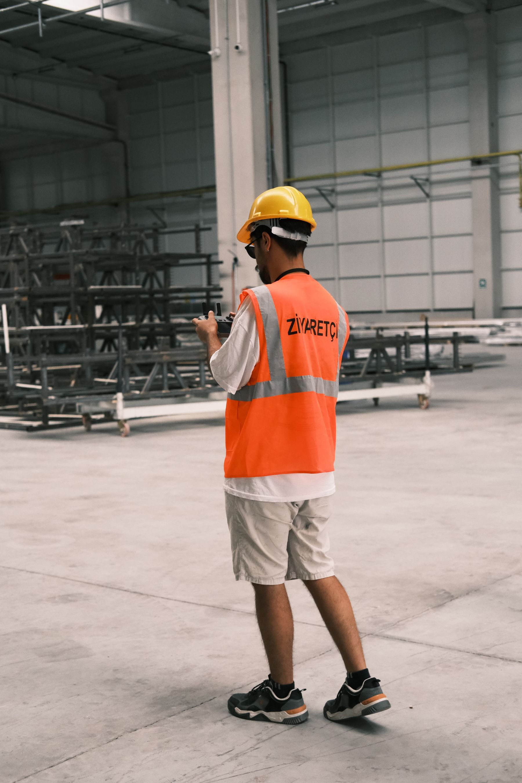 Construction worker wearing a safety helmet and reflective vest at an industrial site