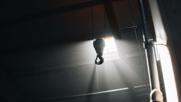 A metal hook suspended in a workshop with dramatic cinematic lighting.