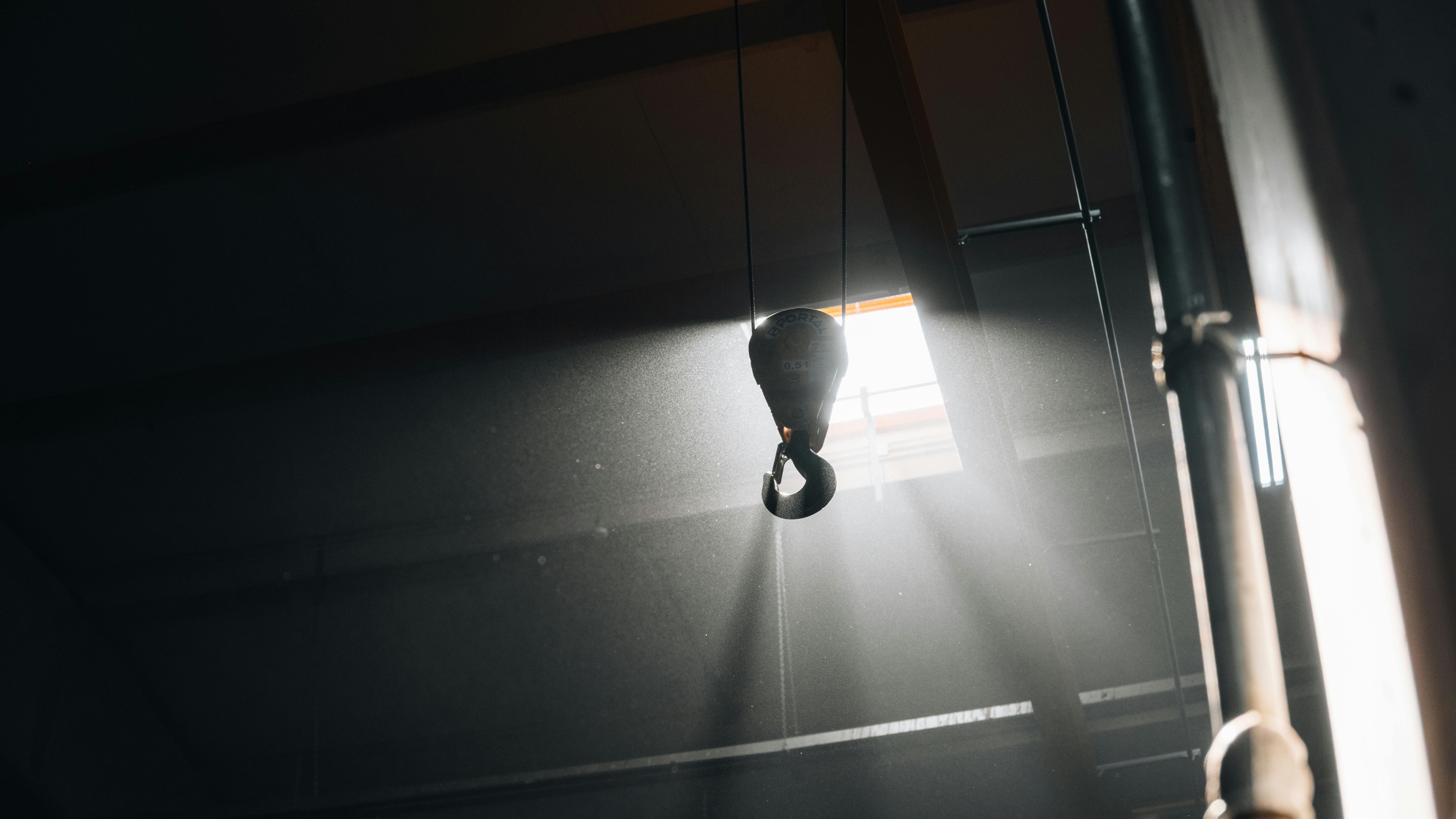 gratis Een metalen haak opgehangen in een werkplaats met dramatische filmische belichting. Stockfoto