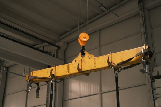 Close-up of a yellow industrial crane used in manufacturing, highlighting strength and machinery.