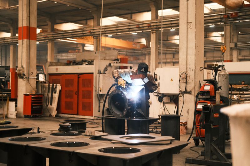 Skilled welder at work in industrial factory on metal frame components