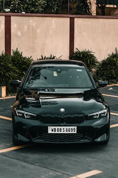 A sleek black BMW parked in an outdoor setting with lush greenery.