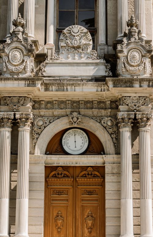 Free Elegant historical building facade with ornate details and a clock above wooden doors. Stock Photo