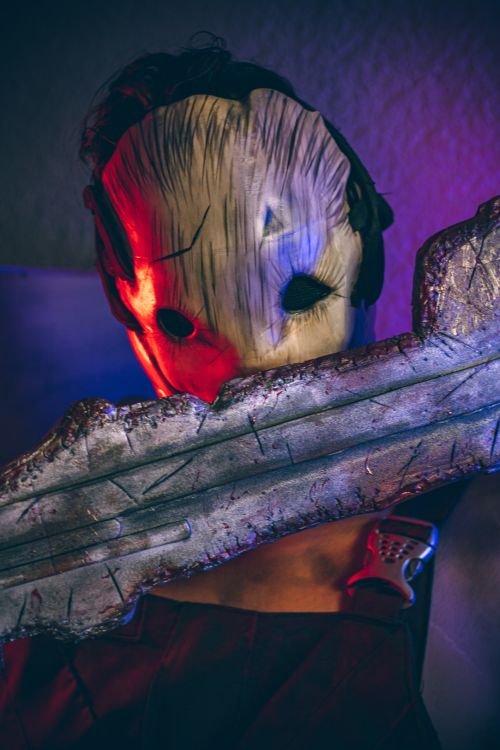 Free Intense shot of a masked cosplayer holding a detailed sword, featuring dramatic lighting. Stock Photo