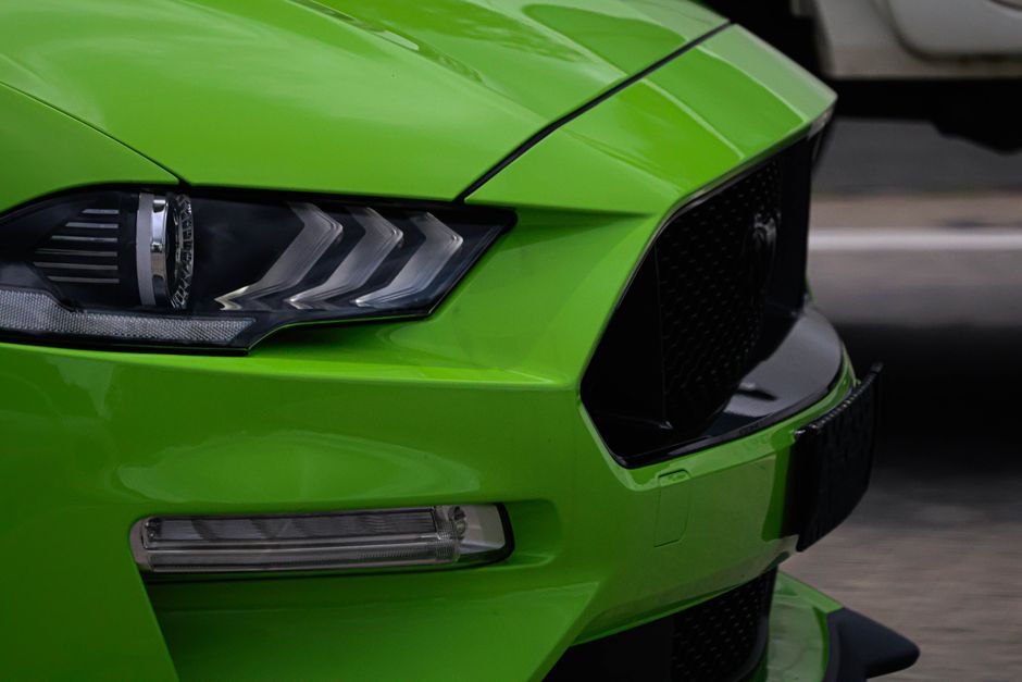 Close-up of a vibrant green sports car front, showcasing sleek design and modern headlights.