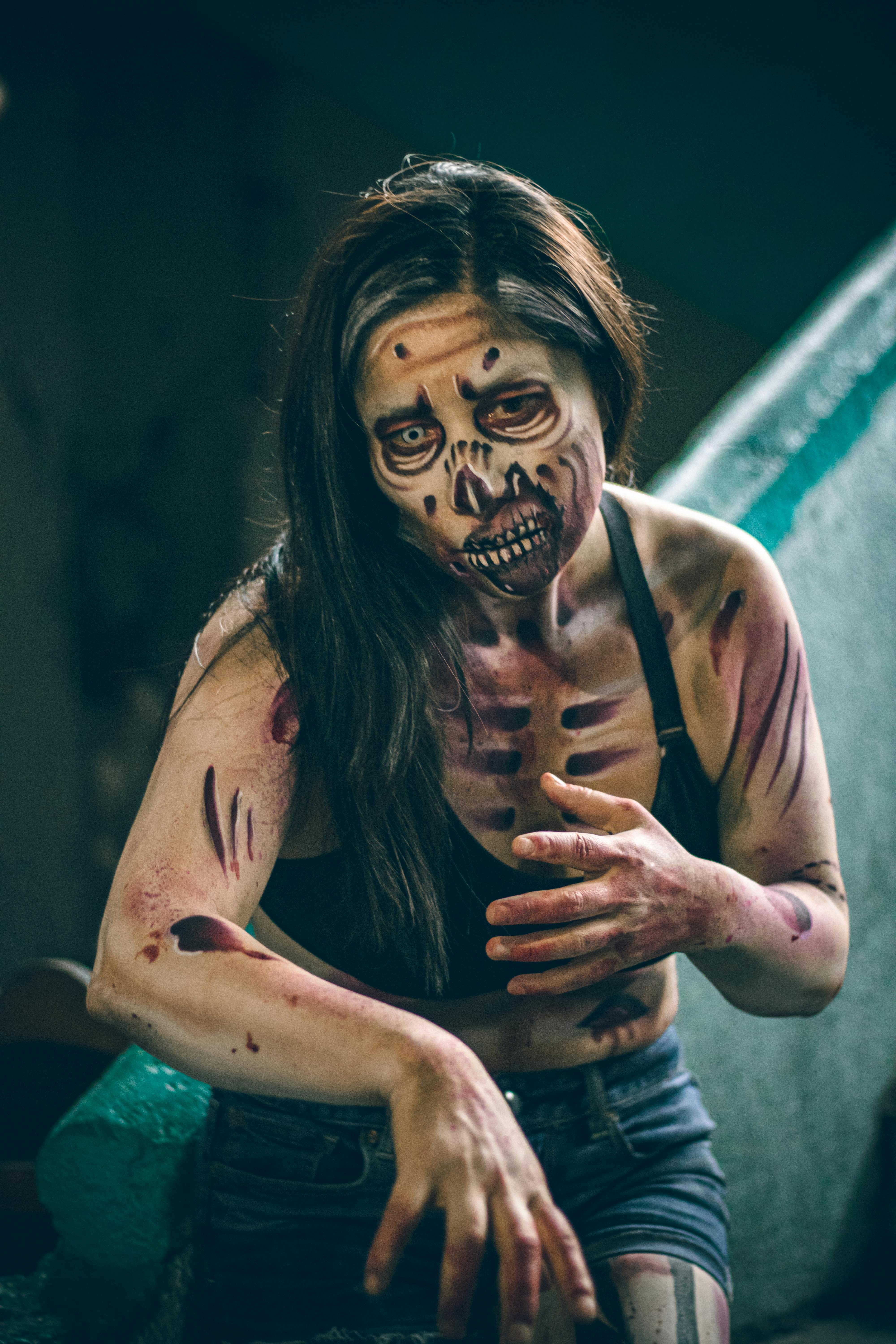 A frightening female zombie in detailed makeup and costume set indoors for cosplay or Halloween.
