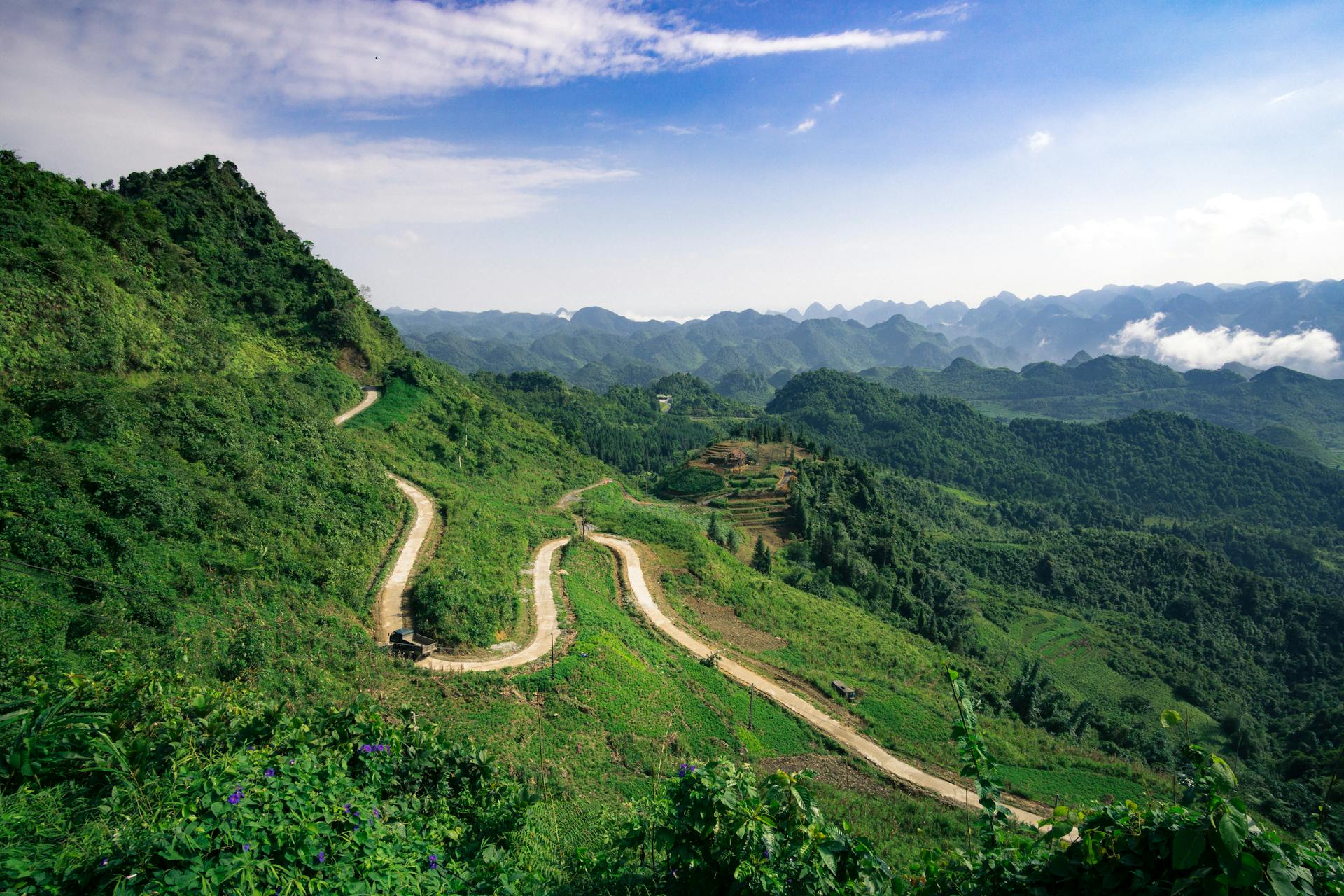 Scenic view of a winding road amidst lush green hills in Hà Giang, Vietnam.