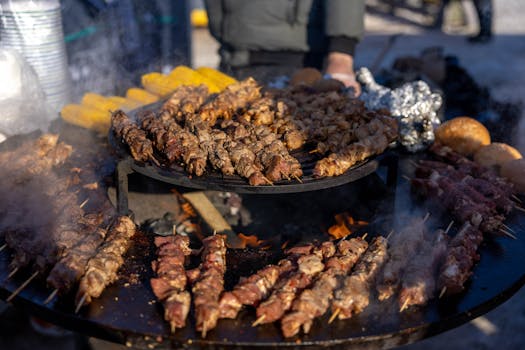Delicious meat skewers grilling over an open fire at an outdoor BBQ.