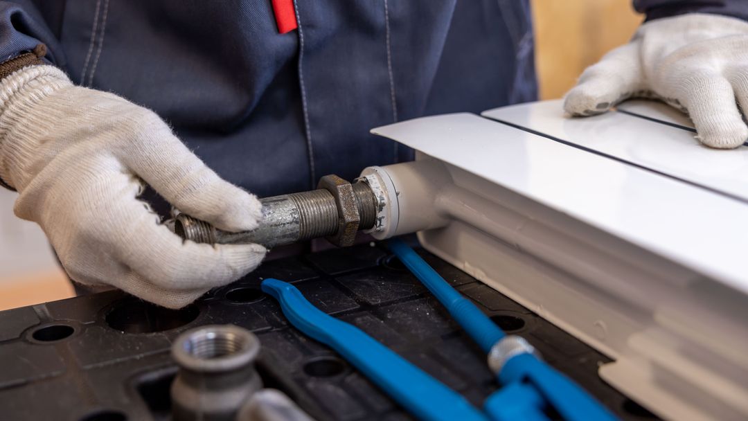 A plumber tightening a pipe connection with a wrench