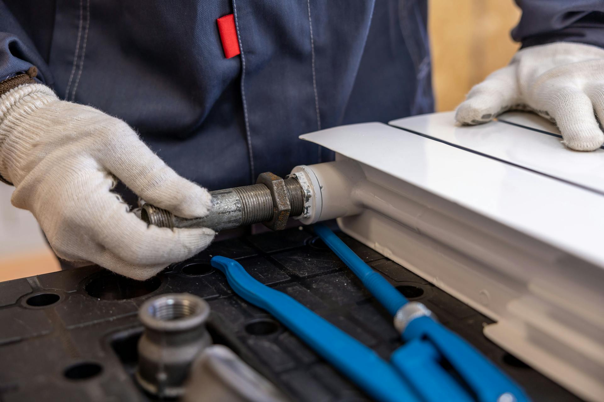 Close-up of a plumber installing a radiator pipe using specialized tools.