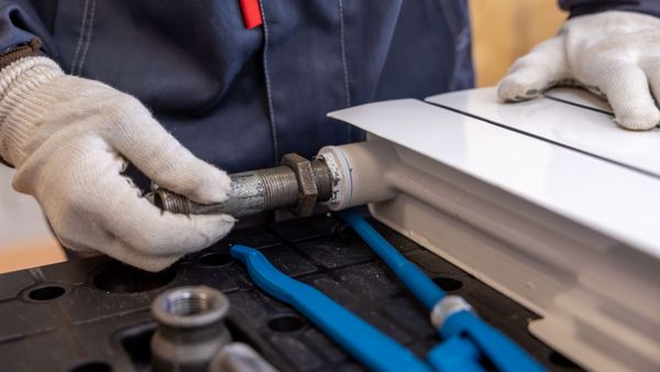 Chauffagiste intervenant sur un radiateur à eau avec ses outils