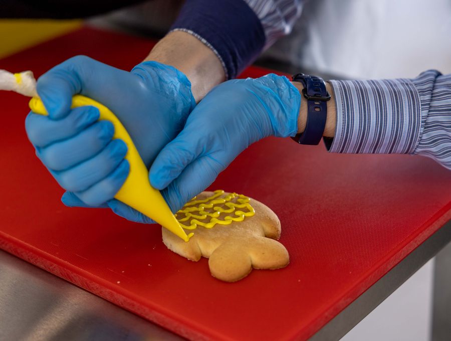 Baker decorating a cookie by hand with icing