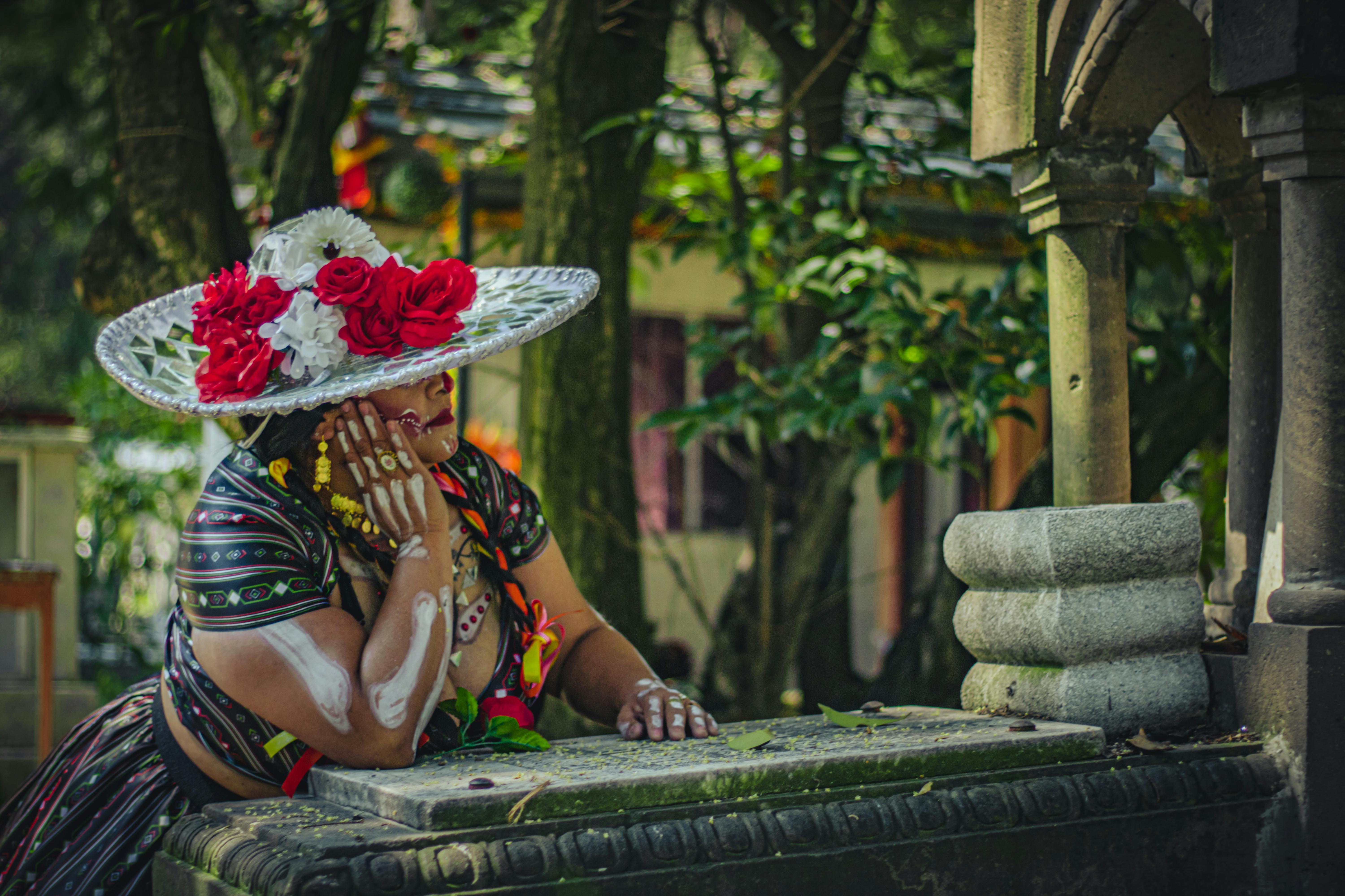 A woman dressed as a Catrina in a cemetery, celebrating Día de Muertos.